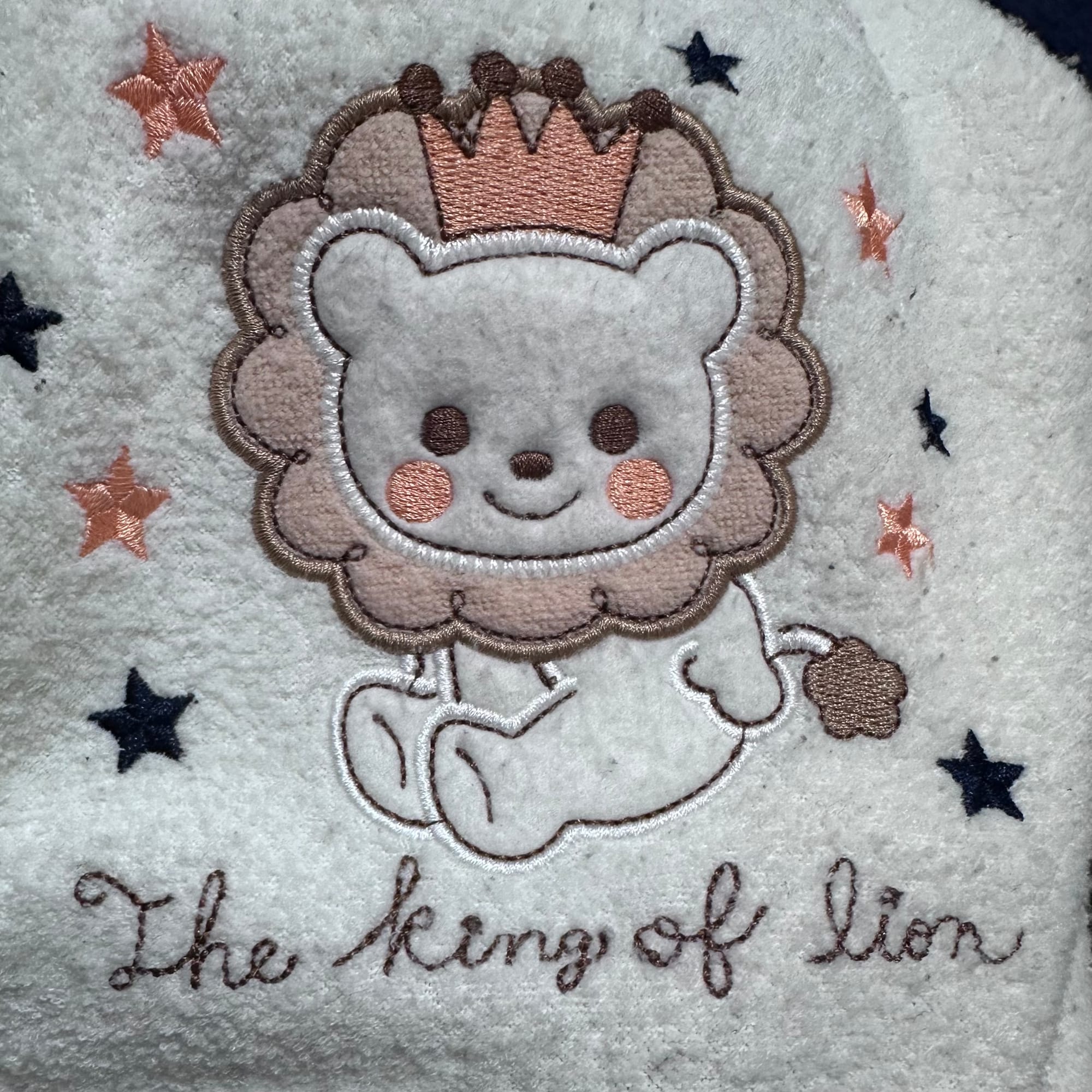 The decal on some baby clothes with a picture of a lion and text that says the king of lion